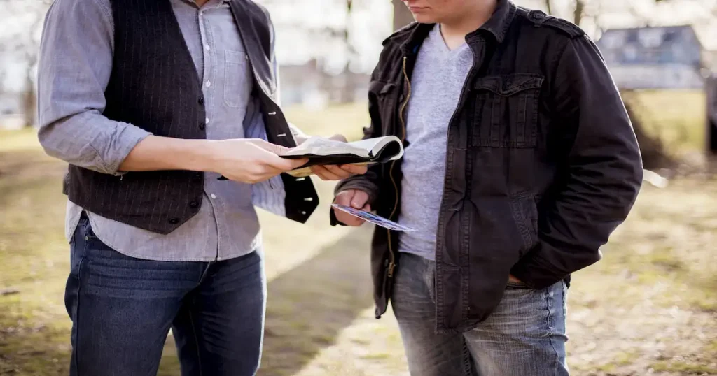 closeup shot two males standing near each other reading bible