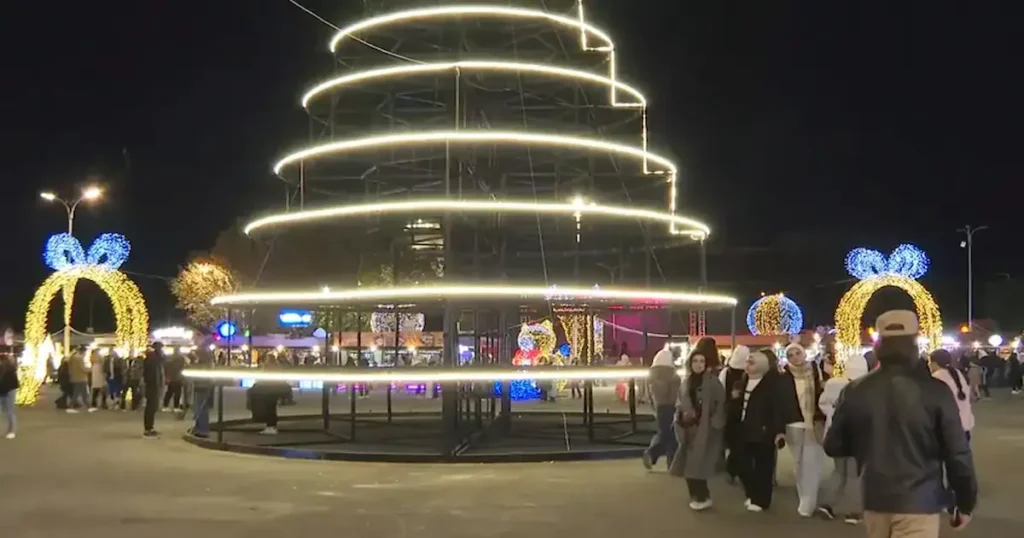 Foto de un árbol de Navidad gigante y personas paseando al rededor