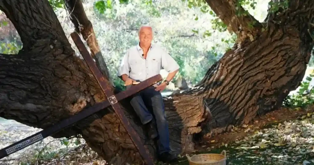 Foto del evangelista Arthur Blessitt posando en un árbol