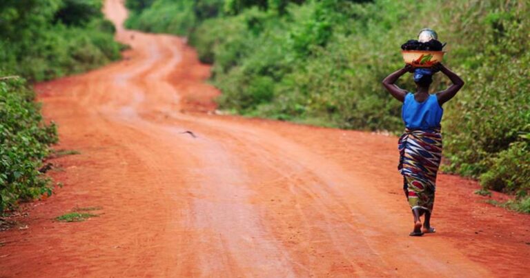 mujer africana transitando un camino de tierra