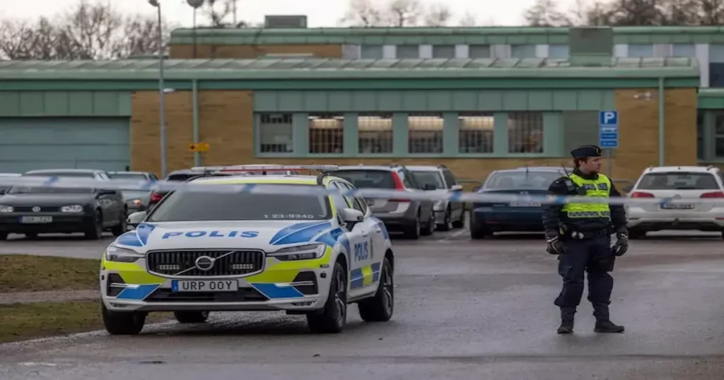 Foto del lugar del tiroteo en Suecia. En el lugar aparecen varios autos y un policía