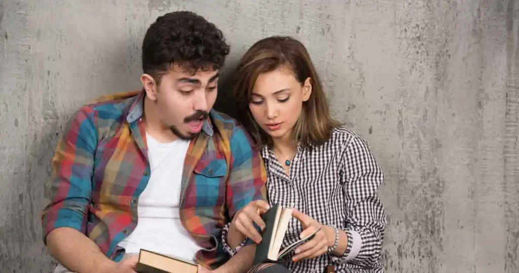 young smiling couple sitting floor with books 1 1
