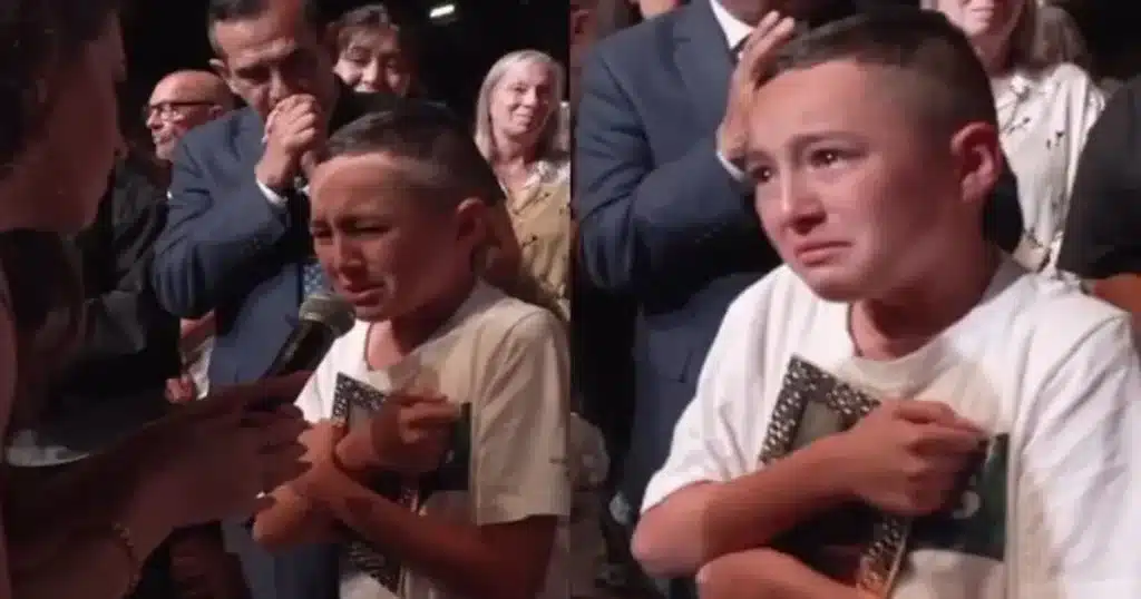 Foto de menino com os olhos marejados segurando uma foto de sua mãe